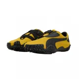 Championes Puma modelo Mostro OG Prime, color amarillo con detalles en negro. Presentan un diseño distintivo con suela de goma con relieve de tachones, cierre de velcro y la icónica franja lateral de la marca.