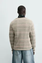 Camiseta de manga larga con cuello redondo y ajuste relajado, confeccionada en tejido de punto con estructura abierta y patrón de rayas horizontales.