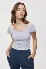 Remera blanca de corte ajustado y largo cropped, con escote redondo amplio y mangas cortas.