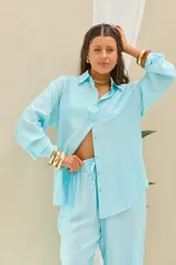 Camisa lisa celeste de manga larga con cuello camisero y cierre frontal de botones.