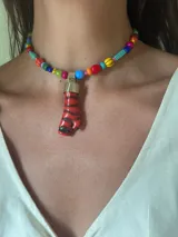 Collar corto de cuentas de colores con dije colgante de coral rojo con vetas negras.