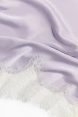 Pañuelo triangular de satén color lila con ribete de encaje blanco en los bordes y diseño para atar.
