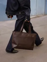 Cartera tipo tote de cuero graneado, con diseño clásico y espacioso. Cuenta con doble asa de hombro, bolsillo frontal con cierre magnético, bolsillo trasero con cierre metálico y compartimento principal con cierre. Interior forrado con múltiples bolsillos organizadores.