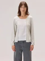 Remera de manga larga con diseño combinado, presentando un panel central de lino en color blanco y laterales de algodón con spandex en tono gris melange. Posee cuello redondo y detalles de vivos en contraste.