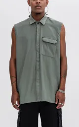 Camisa sin mangas de corte oversize, color verde militar, con cuello clásico, cierre frontal con botones ocultos y un bolsillo tipo cargo en el pecho con solapa y remaches metálicos.