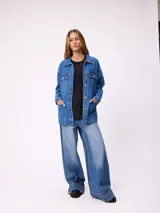 Campera de jean de corte oversize, color azul lavado, con cierre frontal de botones metálicos, bolsillos frontales con solapa en el pecho y bolsillos laterales inferiores.
