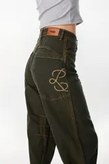 Jean baggy de tiro alto y pierna recta y ancha, color verde militar con efecto acid wash. Presenta bolsillos traseros grandes con costuras destacadas y un monograma bordado en el bolsillo izquierdo.