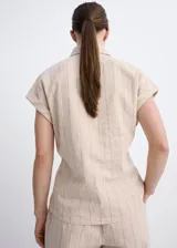 Camisa de lino y algodón color beige con estampado de raya diplomática, cuello camisero, manga corta y detalle de nudo en la cintura con cierre delantero de botones.