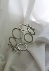 Pulsera plateada con eslabones circulares texturizados y apliques de estrás.