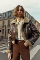 Pantalón de tiro alto color marrón oscuro, con corte flare (campana) y nervio marcado en el frente de ambas piernas. Presenta bolsillos delanteros y bolsillos de plastrón en la espalda.