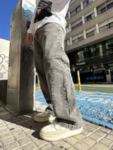 Pantalón de jean con corte baggy y diseño balloon, de color gris lavado con efecto desgastado. Presenta costuras laterales curvadas y una silueta amplia y holgada.