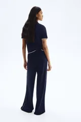 Pantalón de tejido liso color azul marino, de corte amplio y tiro alto con elástico en la cintura. Presenta una fina línea vertical blanca a lo largo de cada costura lateral exterior.