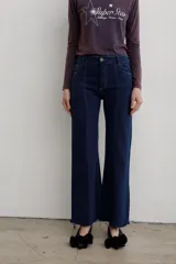 Jean de denim azul marino con tiro medio, corte recto y costuras pespunteadas a lo largo de las piernas. Presenta dobladillo deshilachado.