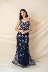 Vestido largo de tul azul con bordado de flores en tonos ocre y rosa pálido. Tiene breteles finos, corte al cuerpo y falda con godets y ruedo armado.