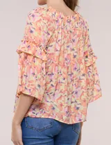 Blusa holgada de gasa estampada en tonos de amarillo, naranja y fucsia con diseño floral. Presenta escote redondo fruncido y mangas tres cuartos acampanadas con volados.