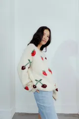 Buzo de lana merino color crema con diseño tejido de frutillas y cerezas en tonos rojos y bordó. Presenta cuello redondo, mangas largas y un corte holgado.