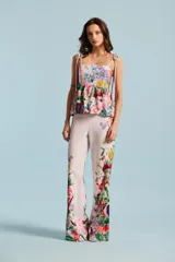 Pantalón Natalia Antolín de corte recto y tiro alto, color rosado claro con estampado floral colorido en la parte inferior de las piernas.