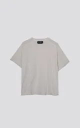 Remera de manga corta y cuello redondo, color beige claro, con textura de tejido cuadriculado sutil y corte regular. Presenta un detalle de costura o recorte en la zona de los hombros.