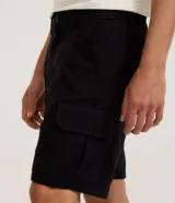 Bermuda cargo negra confeccionada en sarga de algodón, con cintura tradicional, cierre de cremallera y botón, y bolsillos laterales útiles.