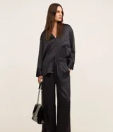 Pantalón wide leg de cintura alta, confeccionado en tejido satinado color negro, con elástico y lazo en la cintura y bolsillos delanteros.