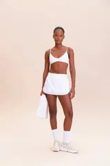 Pollera deportiva color rosa fucsia, con estampado en relieve de texto. Es de corte corto con ruedo redondeado y cuenta con shorts internos.