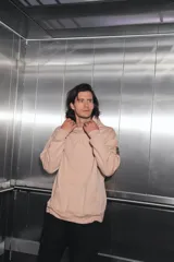 Buzo oversize color nude confeccionado en frisa, con capucha amplia, bolsillo canguro, terminaciones de puño y ruedo con rib, y logo de la marca bordado en el centro delantero.