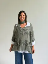 Sweater de punto color verde oliva con diseño de paneles horizontales de encaje floral, corte holgado y mangas tres cuartos. Incluye una bufanda del mismo tono y tejido, y se presenta superpuesto sobre una camisa blanca de cuello clásico.