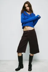 Jersey de punto color azul eléctrico con escote en pico, manga larga y detalle de costuras marcadas en los hombros. Presenta un corte ligeramente cropped con puños y ruedo acanalados.