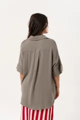 Camisa verde de silueta oversize con cuello camisero y manga 3/4. Tiene bordados de coral y caracol en el frente y botones a tono.