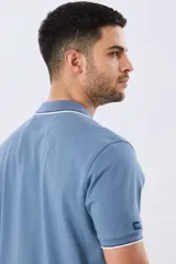 Remera polo de piqué azul marino, con cuello y puños de mangas cortas con ribete blanco en contraste, cierre frontal de dos botones y pequeño logo bordado en el pecho.
