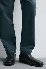 Bota estilo Chelsea de cuero negro, con elásticos laterales y suela plana a tono con ligero tacón.