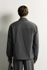 Sobrecamisa regular fit color gris, con cuello solapa, manga larga con puño abotonado, bolsillos de vivo en la cadera y cierre frontal con cremallera de doble dirección.