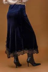Falda midi de terciopelo azul marino con corte asimétrico y terminación de encaje negro en el ruedo.