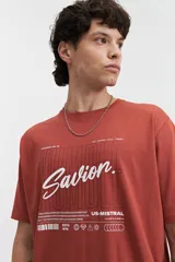 Remera blanca de manga corta con estampado frontal que incluye la palabra 'Savior' en letras cursivas negras y otros textos en tipografía sans-serif. Corte regular.