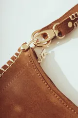Cartera de hombro negra con forma de media luna, confeccionada en material con textura de pelo o cuero. Presenta costura decorativa gruesa en el borde y correa ajustable con herrajes metálicos plateados.