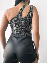 Top negro brillante de un solo hombro con abertura en el hombro izquierdo.