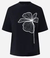 Remera de algodón marca Cortelle, con calce regular, cuello redondo y mangas cortas. Presenta un diseño minimalista con un estampado floral lineal en color blanco sobre fondo negro.