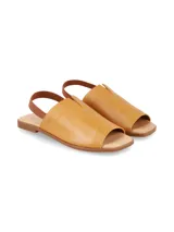 Sandalia plana de cuero graneado color mostaza, con tira elástica en el talón, diseño destalonado y suela baja.