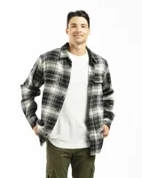 Sobre camisa de franela a cuadros en tonos gris, negro y blanco, con cuello clásico, cierre frontal con botones, dos bolsillos con solapa en el pecho y corte recto. Usada sobre una remera blanca y pantalón cargo verde.