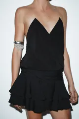 Falda pantalón corta color beige claro, de tiro medio, con efecto drapeado en la cintura y volantes superpuestos en el ruedo.