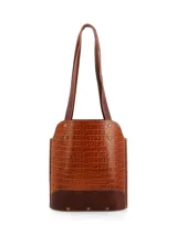 Bolso matero Hush Puppies de cuero en tono tostado con textura símil cocodrilo y detalles en marrón oscuro en la base. Cuenta con doble asa larga para hombro y tachas metálicas decorativas.