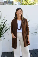Saco abierto tipo cárdigan de punto en color chocolate, con diseño de corte recto, mangas largas y bolsillos frontales aplicados.