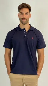 Chomba de piqué color azul marino, con cuello polo, cierre frontal de tres botones y logo bordado en color rojo en el pecho.