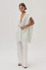 Ruana tejida con detalle de lurex, de diseño abierto y sin mangas, con escote en V profundo y ajuste mediante cinturón en la cintura.