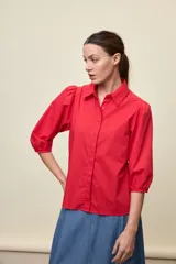Camisa de algodón blanca con cuello camisero, frente abotonado y mangas abullonadas de corte relajado.