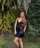 Vestido corto de tela metalizada en tono fucsia con reflejos dorados, con escote en V, diseño de top con triángulos, aberturas laterales en la cintura y doble volado irregular en el ruedo.