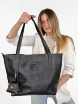 Cartera tote de cuero genuino color negro, con costuras visibles a contratono, asas dobles para hombro, parche frontal con logo grabado y charms colgantes en forma de estrella y mini monedero.