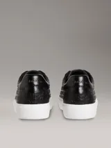 Zapatillas negras de piel sintética con monograma de Calvin Klein grabado en relieve, suela de goma blanca y cordones al tono.