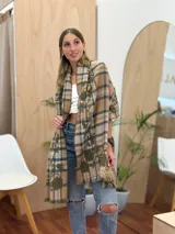 Bufanda rectangular con estampado a cuadros en tonos beige, azul y verde. Tiene flecos en los extremos y un estampado floral en el interior.