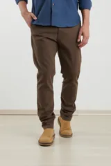 Pantalón chino de hombre, color marrón oscuro, corte slim, confeccionado en algodón con elastano. Presenta triple pespunte en las costuras y botones al tono.